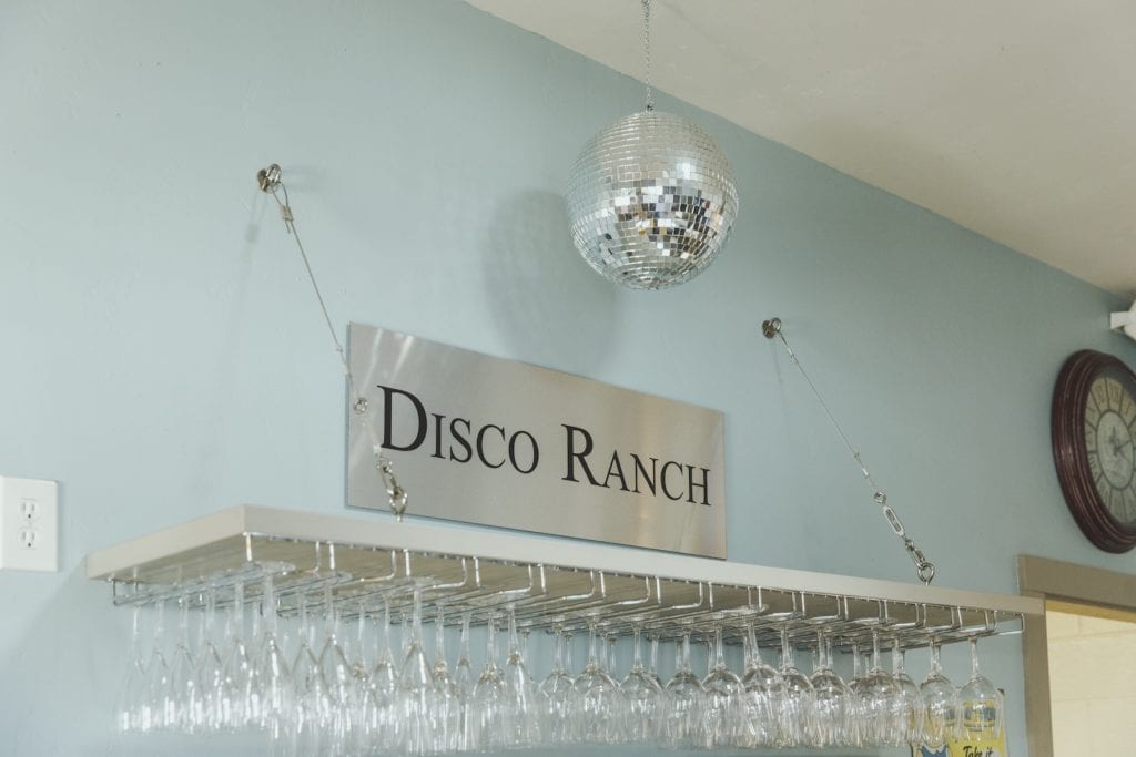 a disco ball above racks of wine glasses